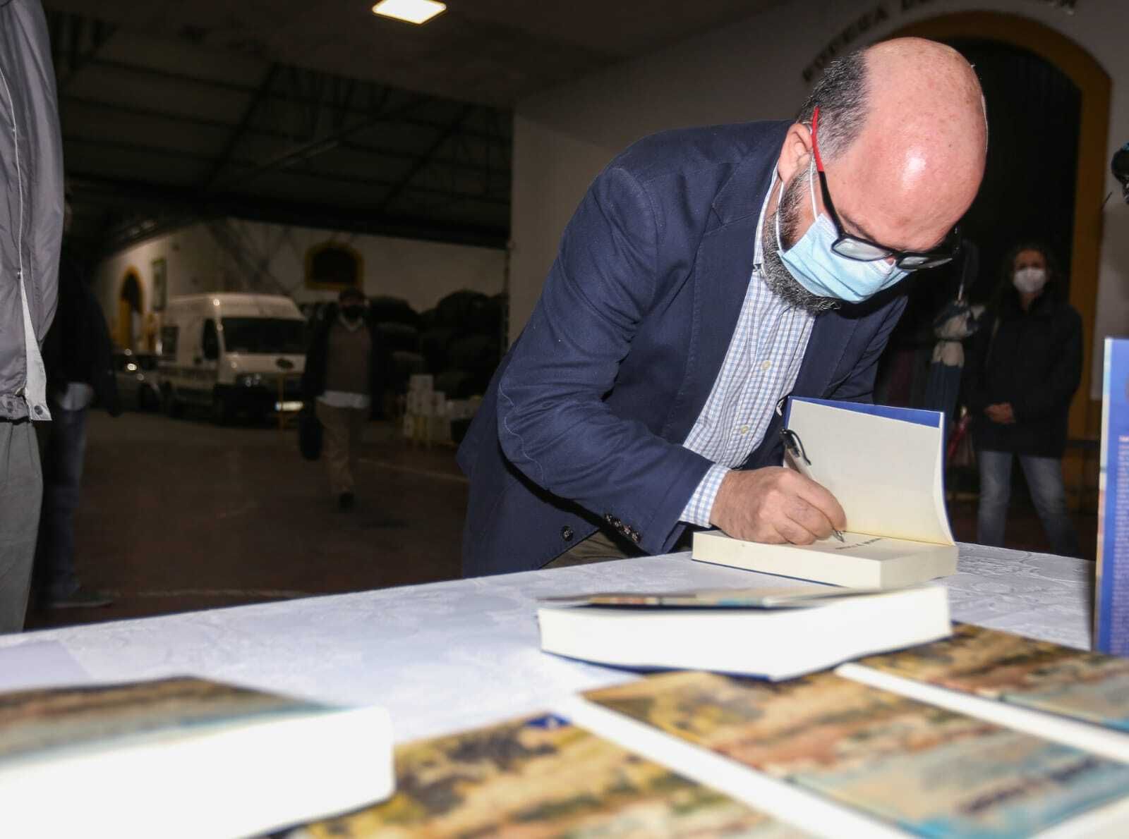 Juan Carlos Rodríguez escribe una dedicatoria en uno de sus libros.