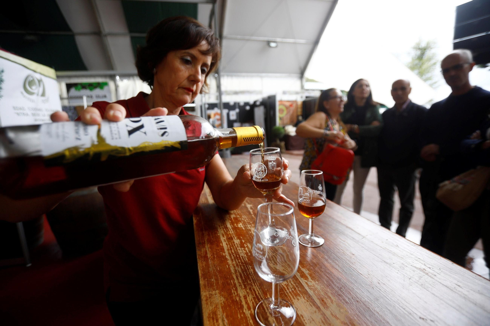 Una mujer sirve una copa de vino dulce.