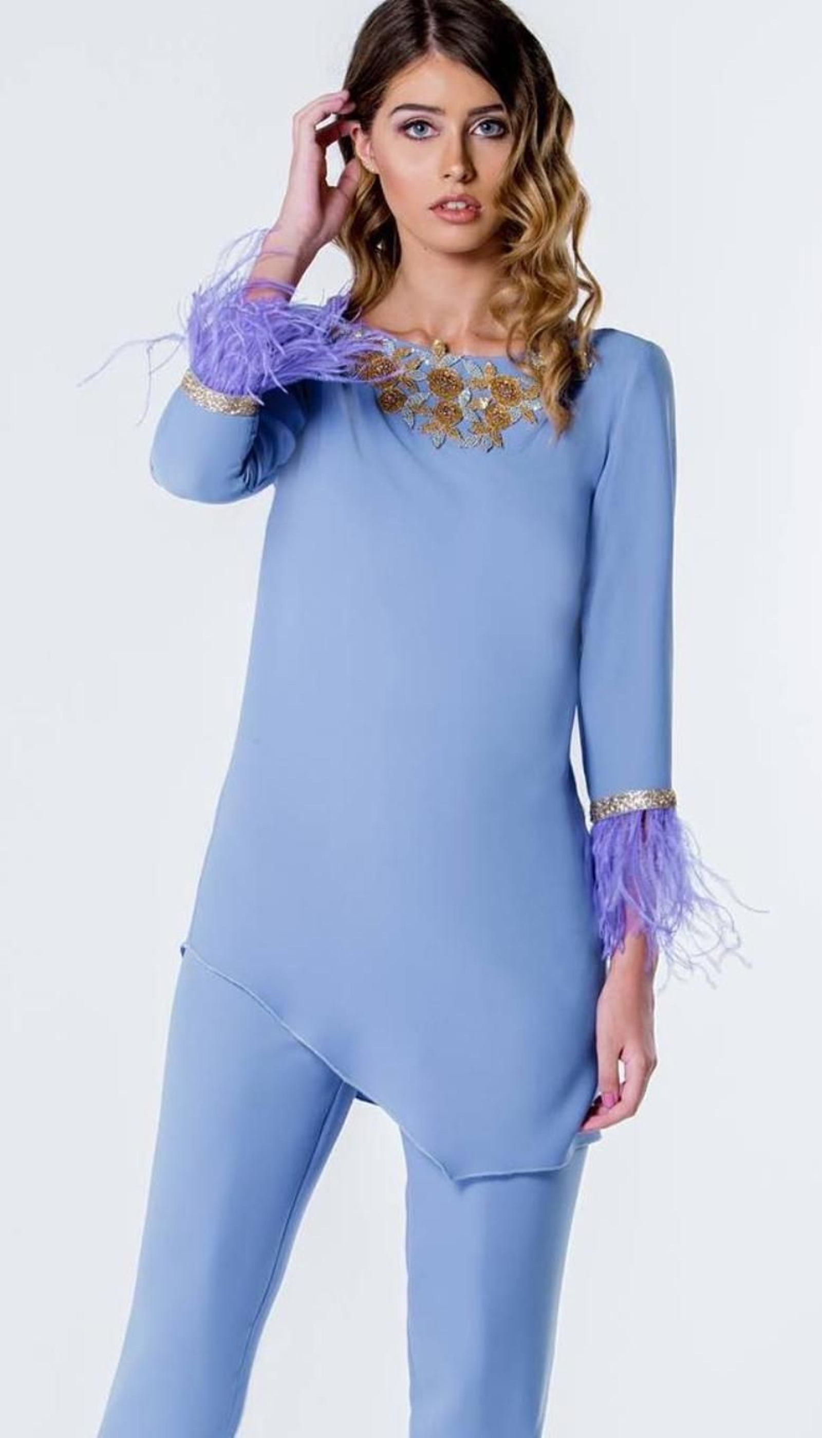 A veces lo que nos sienta mejor no es un vestido entallado sino un conjunto blusa y pantalón. Reporta una apariencia más sofisticada a la par que enfatiza el largo de la pierna y los hombros. Esta propuesta la da la diseñadora Ana Torres, que consigue un resultado espectacular gracias a los apliques dorados y las plumas de los puños.
