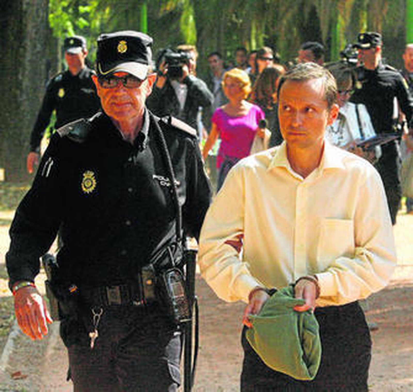 Bretón, esposado y acompañado por un policía, en octubre de 2011, durante la reconstrucción del día de la desaparición.