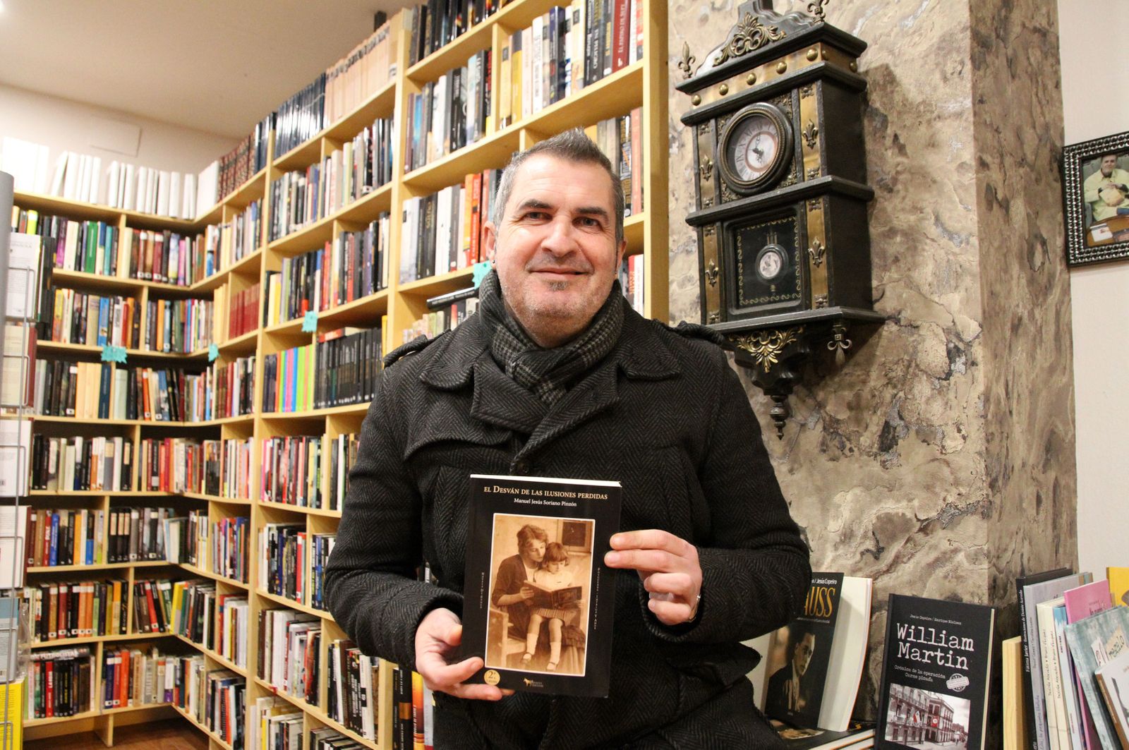 El escritor Manuel Jesús Soriano Pinzón posa en su librería con un ejemplar de su última novela.