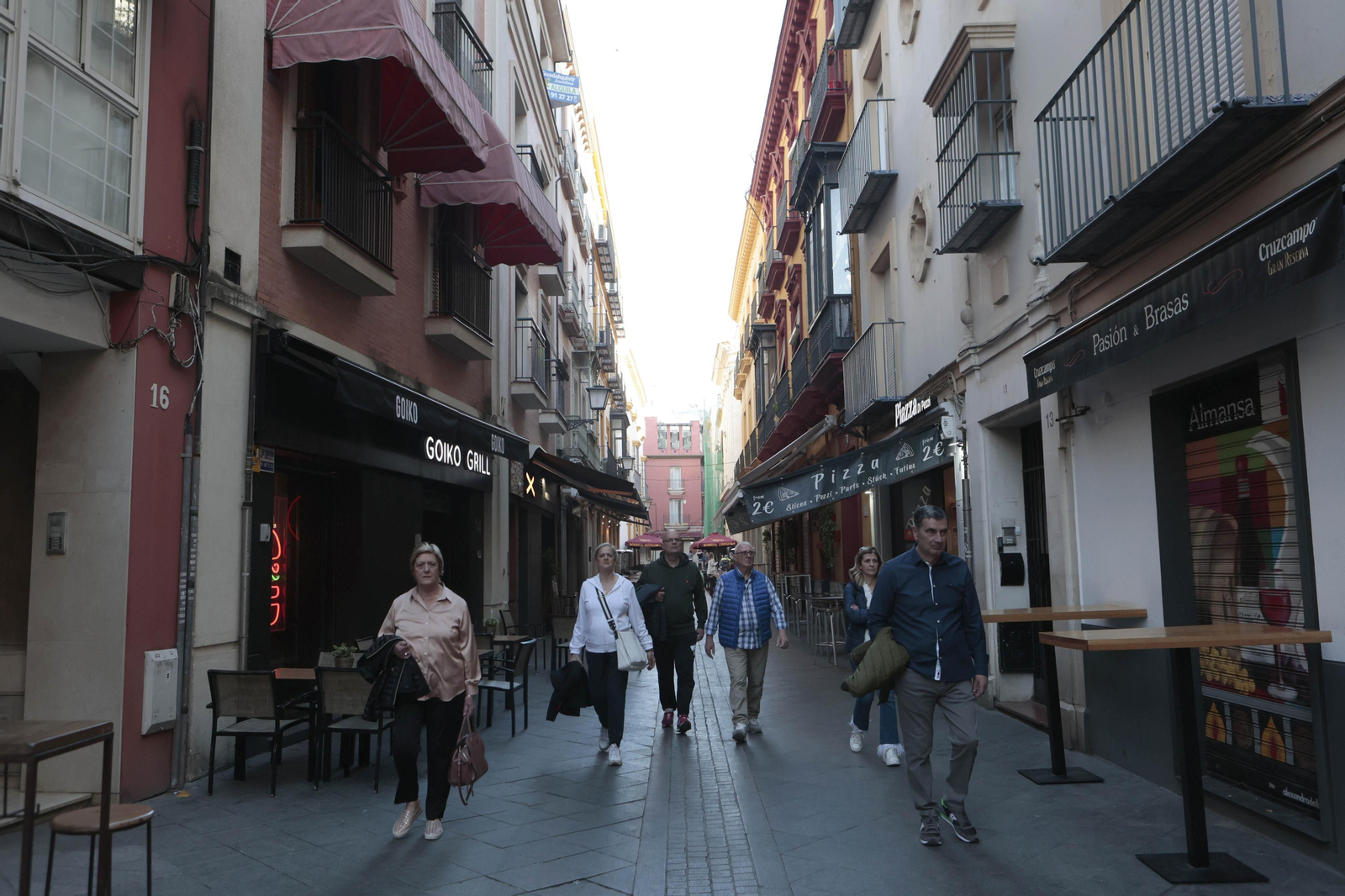 Varios turistas caminan por una céntrica calle repleta de bares.