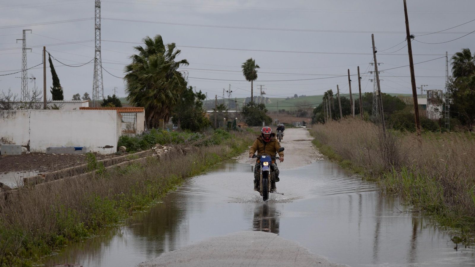 Un motorista cruza un enorme charco en la calle Margarita del Palmar de Troya.