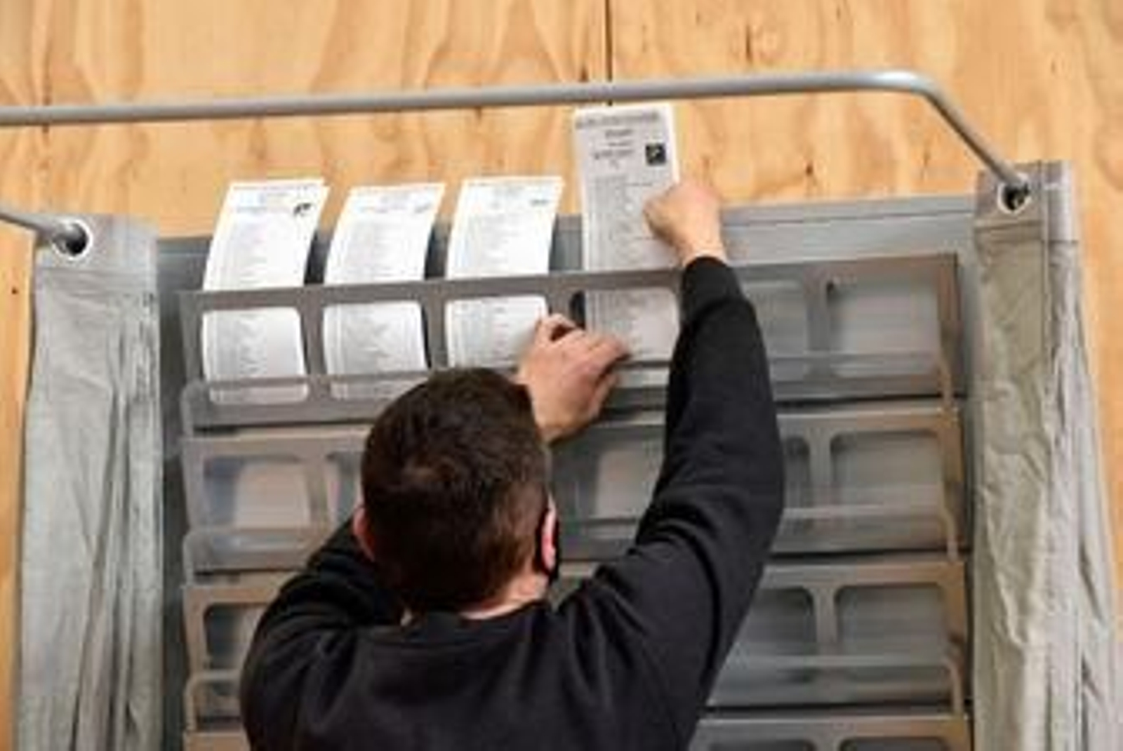 Un trabajador ordena varias papeletas en el dispositivo electoral para los comicios