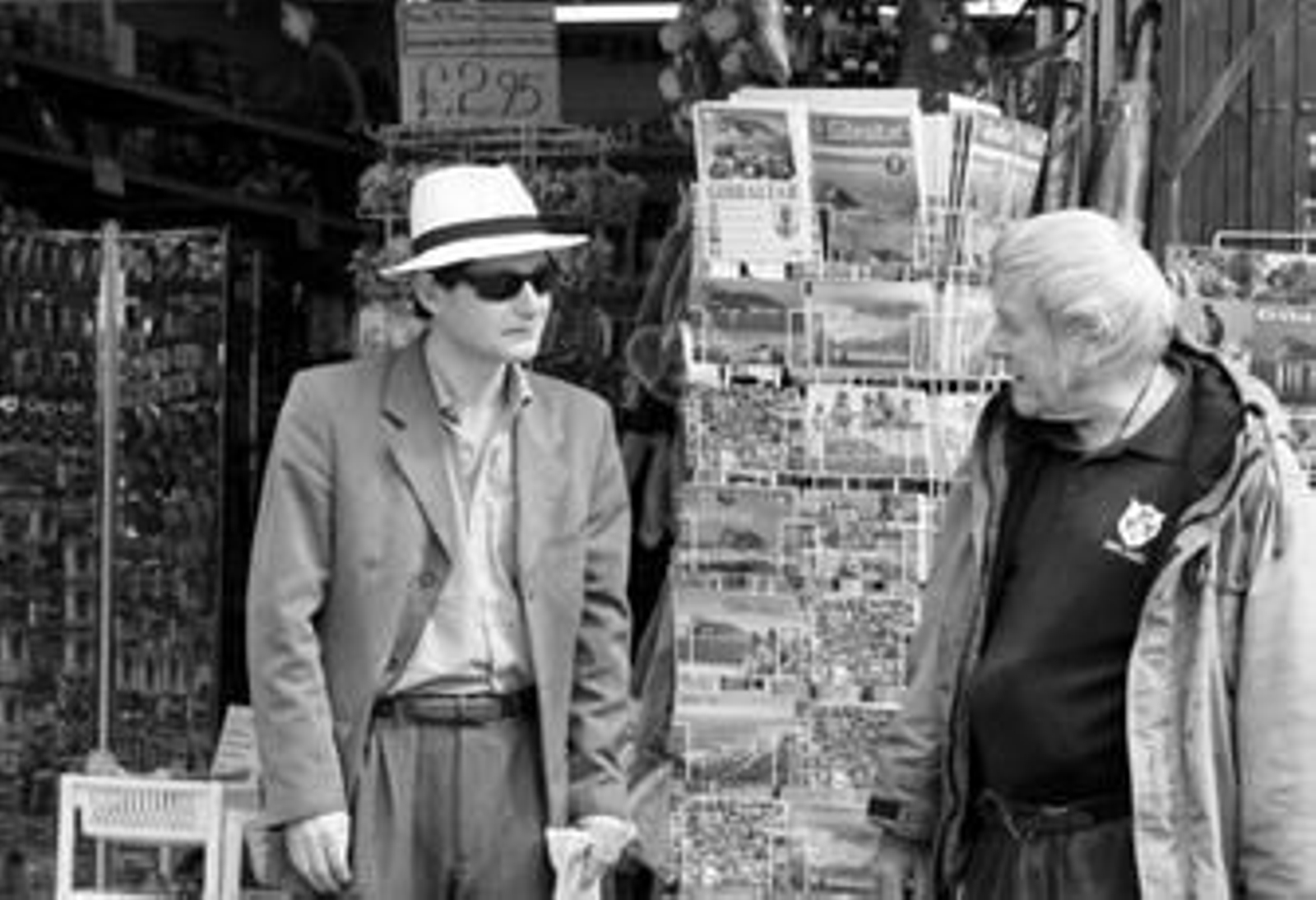 Dos hombres charlan a la entrada de un establecimiento de souvenirs en la calle Real.