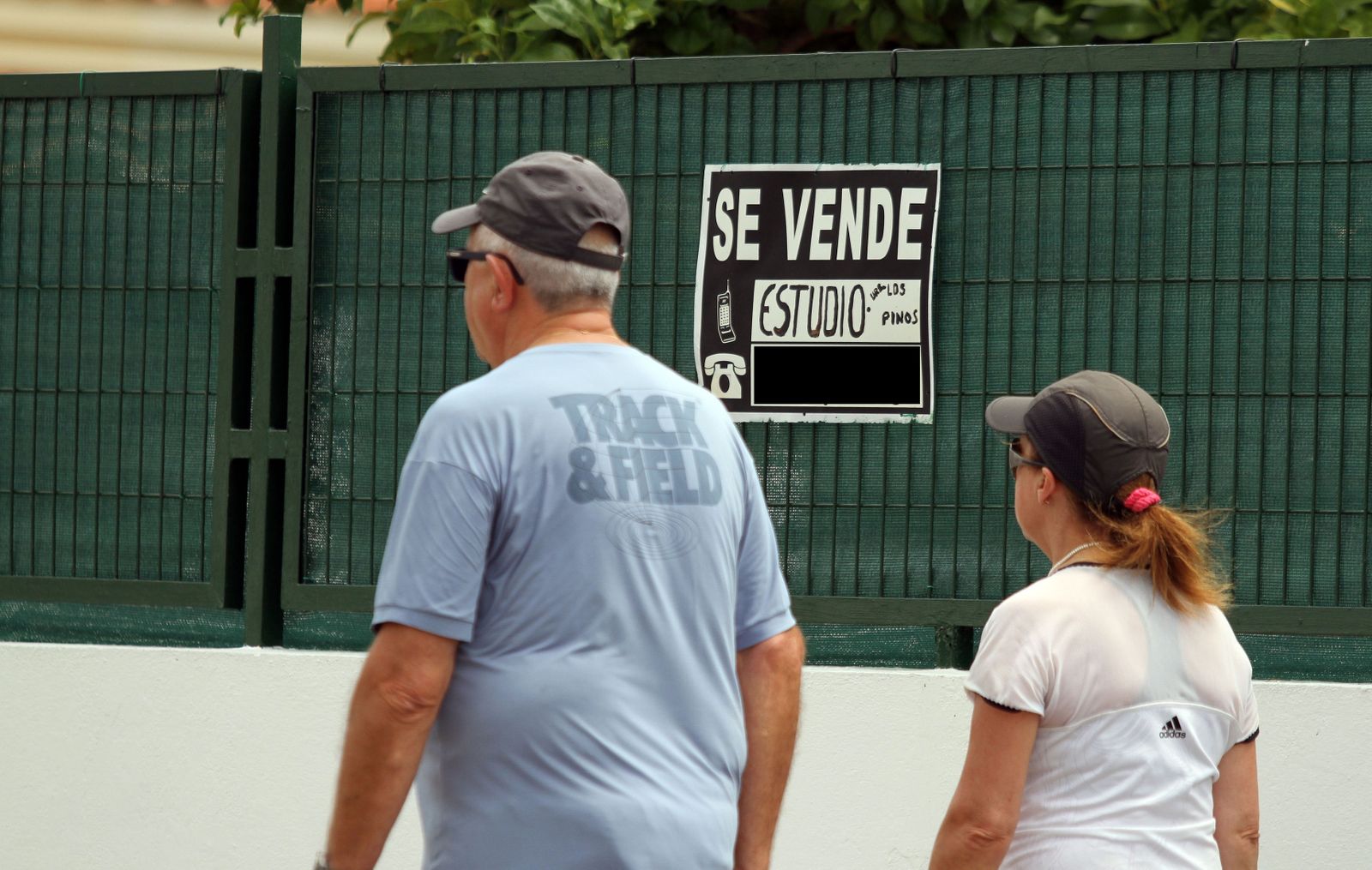 Dos personas pasan frente a un cartel de 'Se Vende' en Granada