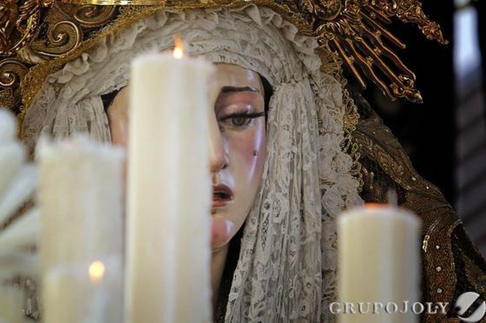 Uno de los cirios de la candelería del palio de la Virgen de la Paz en su Mayor Aflicción deja entrever el bello rostro de María, en pleno llanto.

Foto: Manuel Aranda