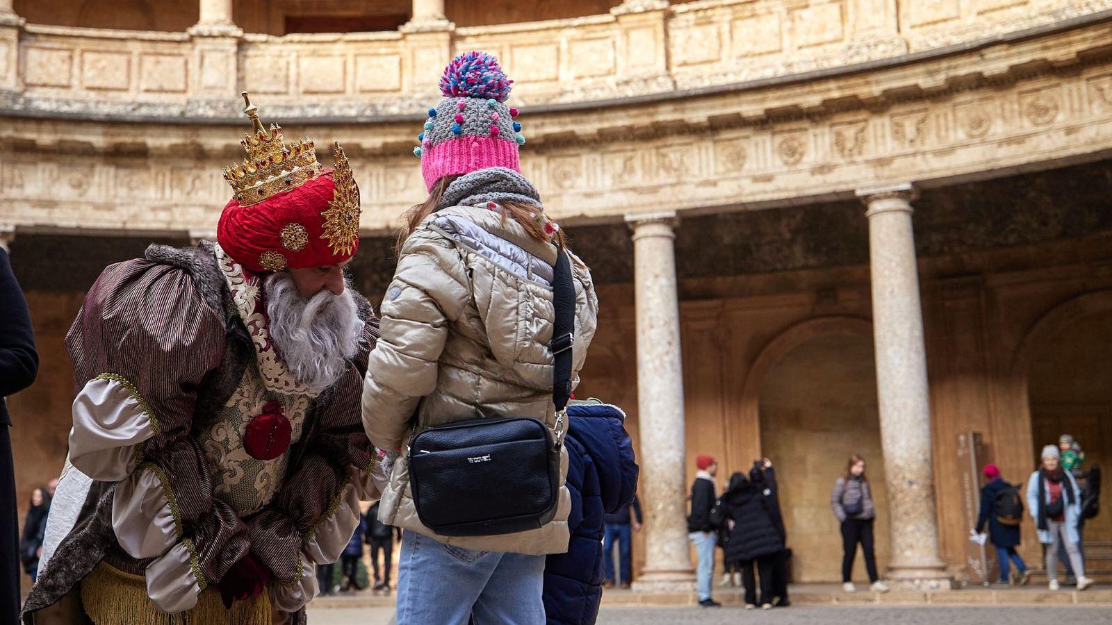 Dos niños se acercan a hablar con Melchor en La Alhambra