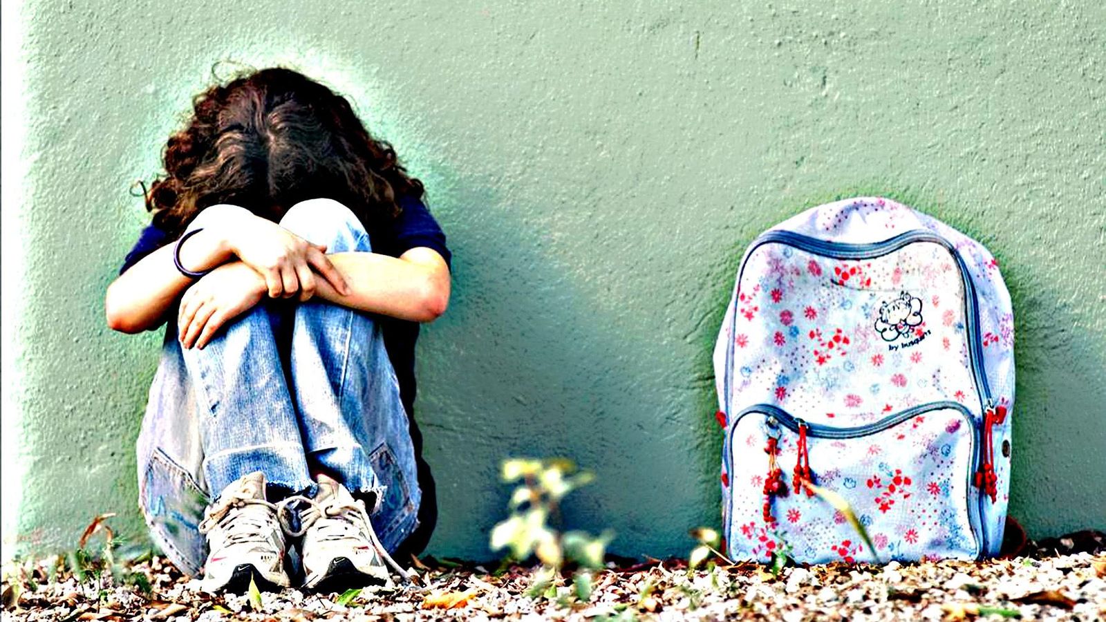 Una niña esconde la cara entre sus piernas.