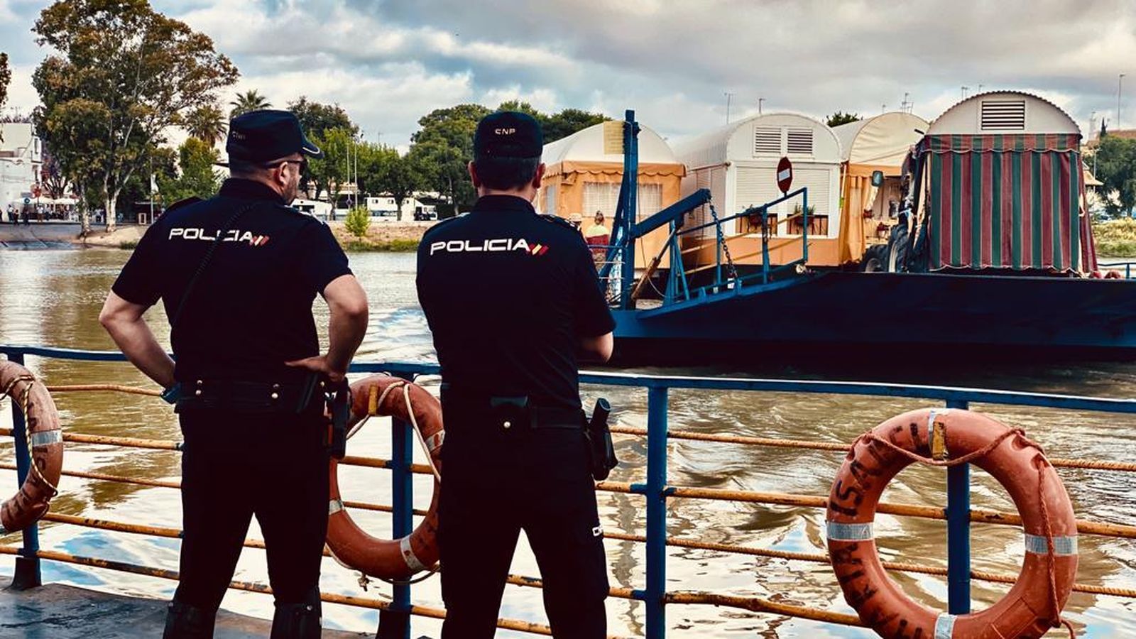 Policías nacionales, atentos al cruce de las hermandades por el Guadalquivir.