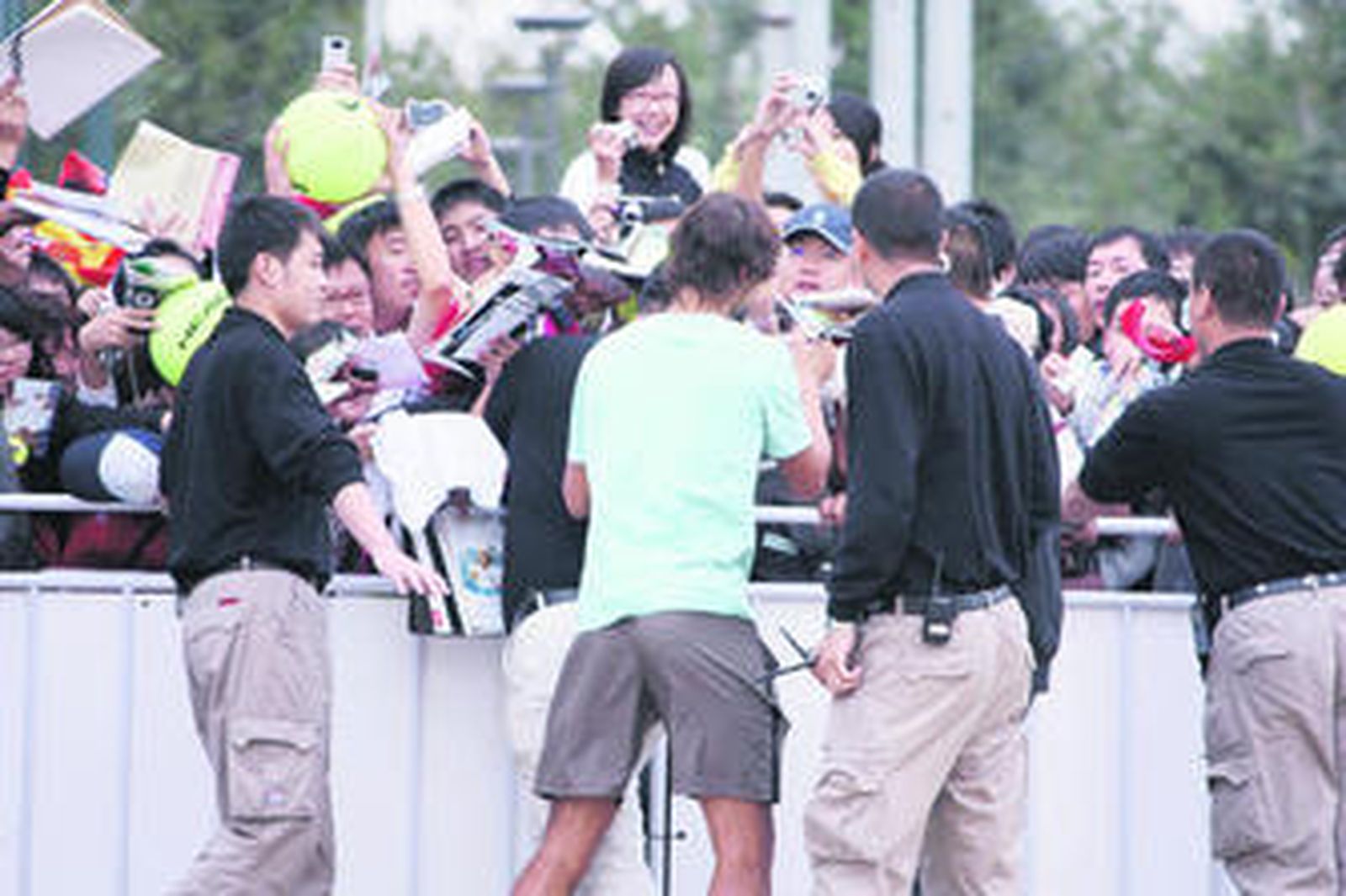 Rafa Nadal firma autógrafos tras su entrenamiento de ayer en Pekín.