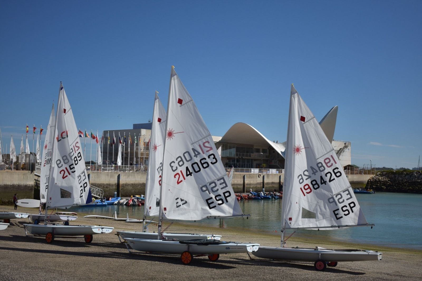 Embarcaciones de vela ligera aguardan en la playa asfáltica de Puerto Sherry.