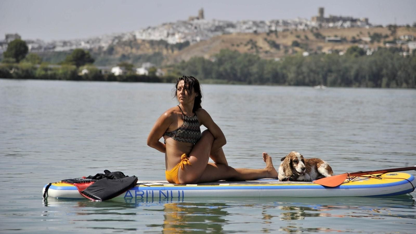 Una mujer practica yoga sobre su tabla de paddle surf en el lago de Arcos