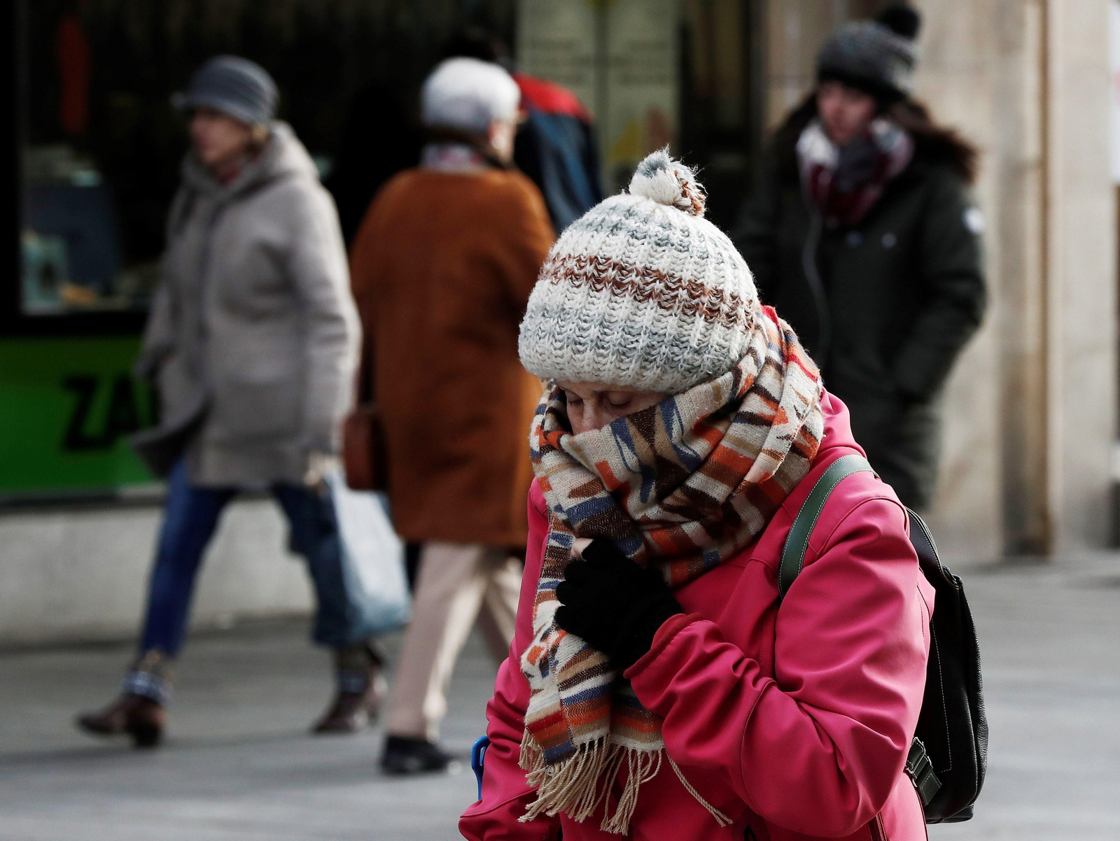 Una mujer se cubre con gorro, guantes y bufandas.