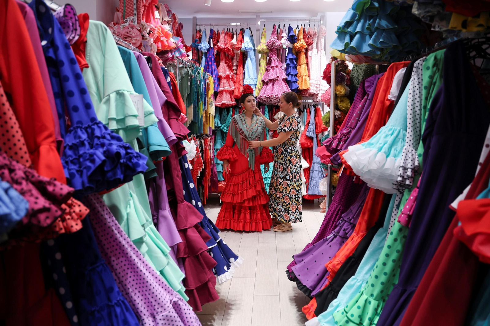 Patricia Moreno, empleada de Viva La Feria, ayuda a Aroa Gómez a elegir traje para la Feria.