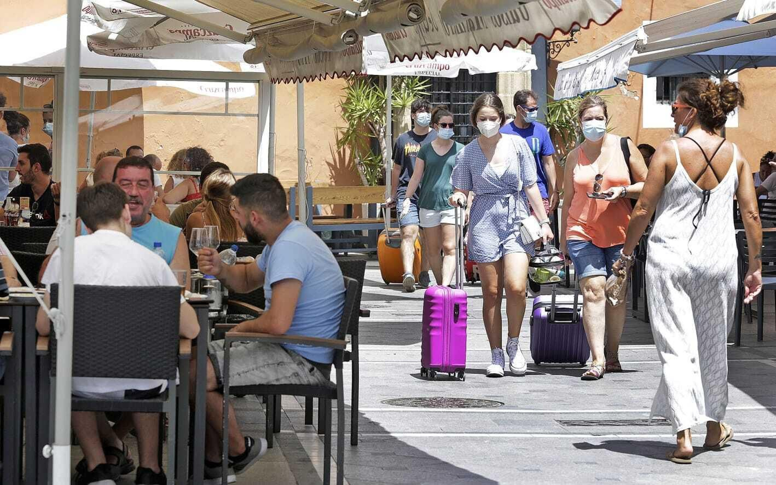 Turistas con mascarilla pasean junto a varias terrazas en Cádiz.