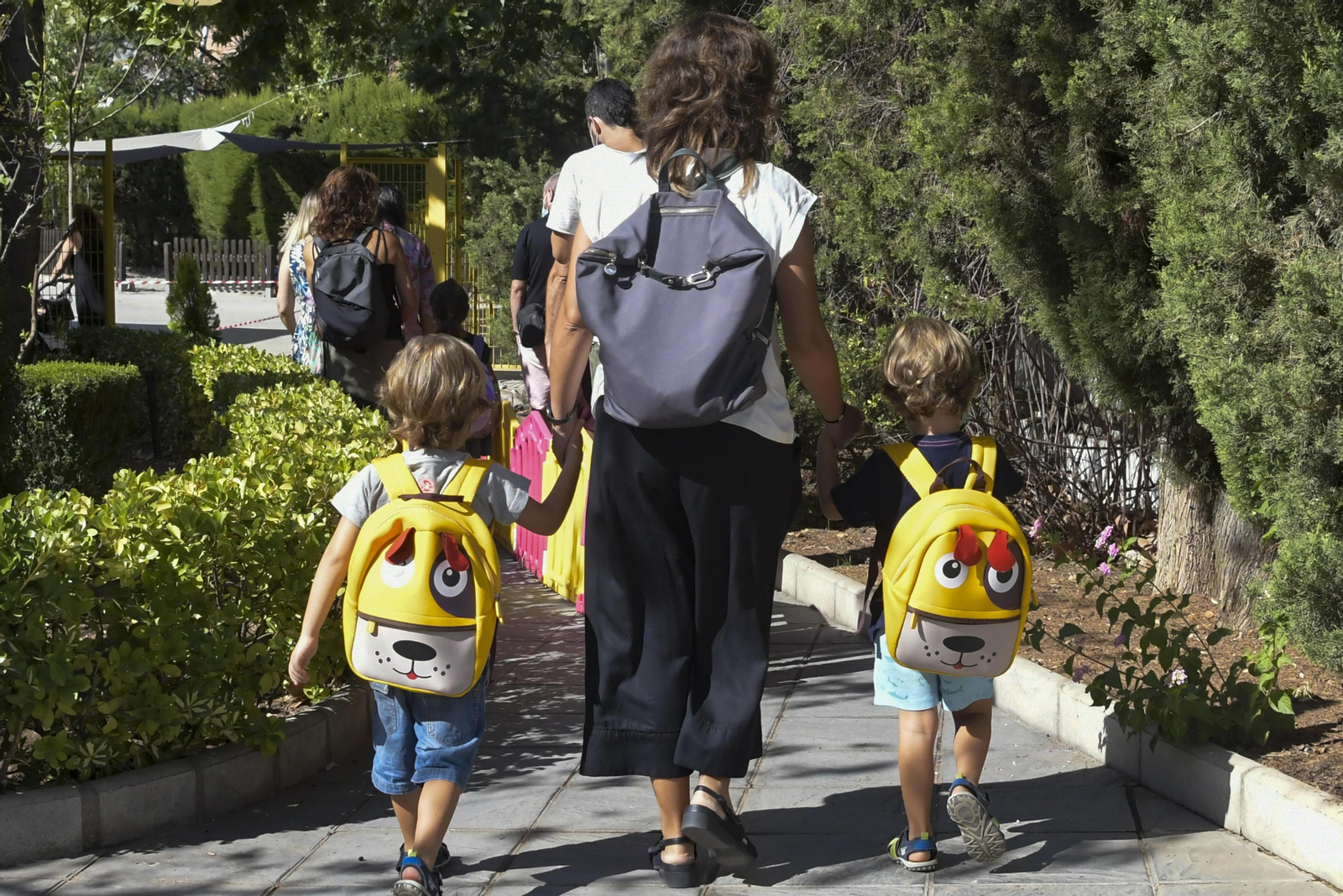 Una madre acompaña de la mano a sus dos hijos al colegio Una madre acompaña de la mano a sus dos hijos al colegio