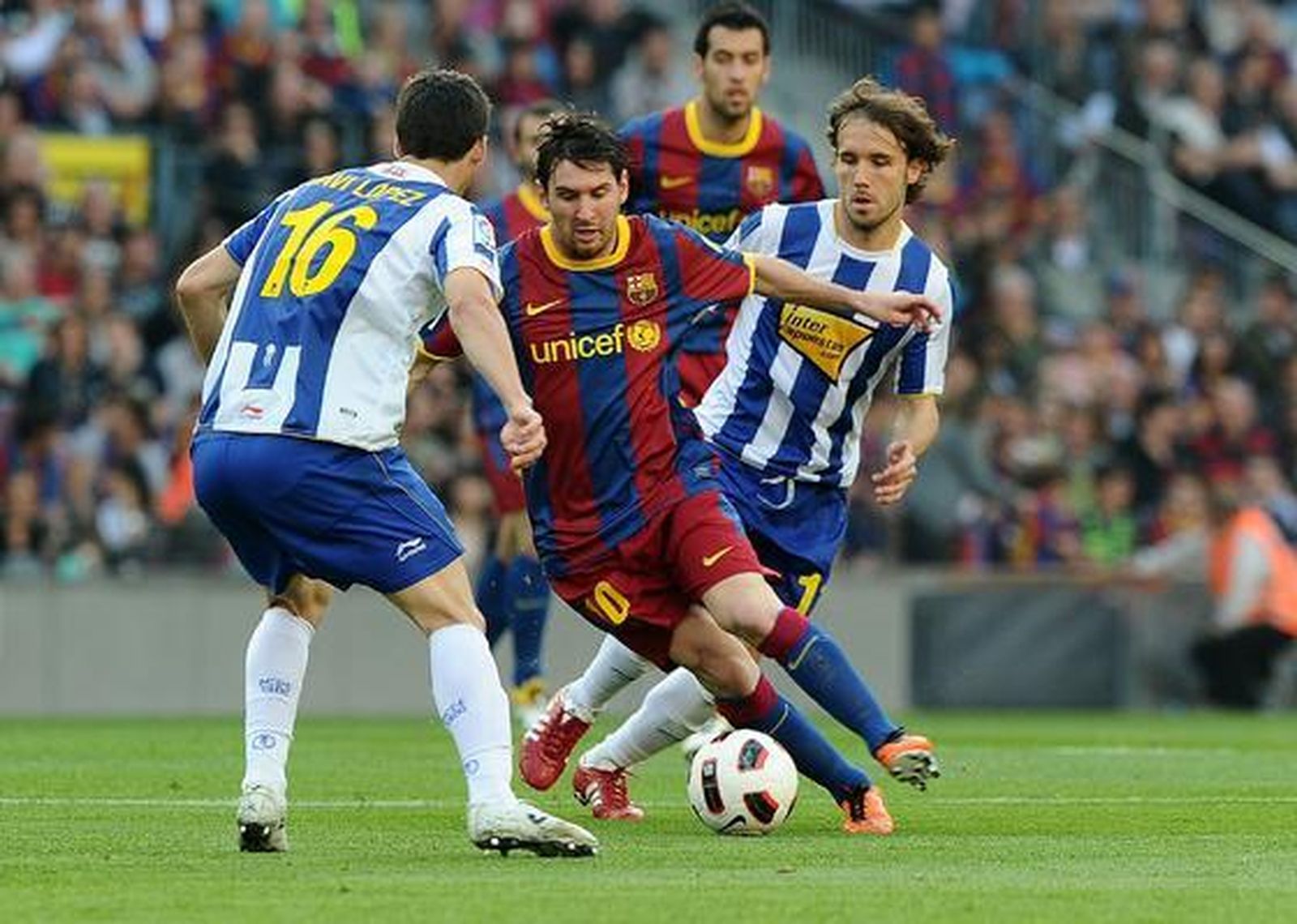 Messi intenta marcharse de dos defensas blanquiazules. / AFP