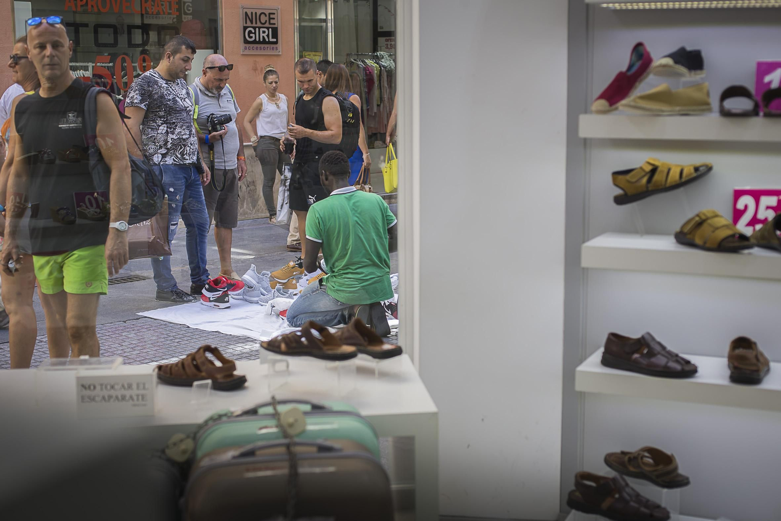 Un vendedor ofrece calzado de marcas falsificados a las puertas de una zapatería de la capital gaditana.