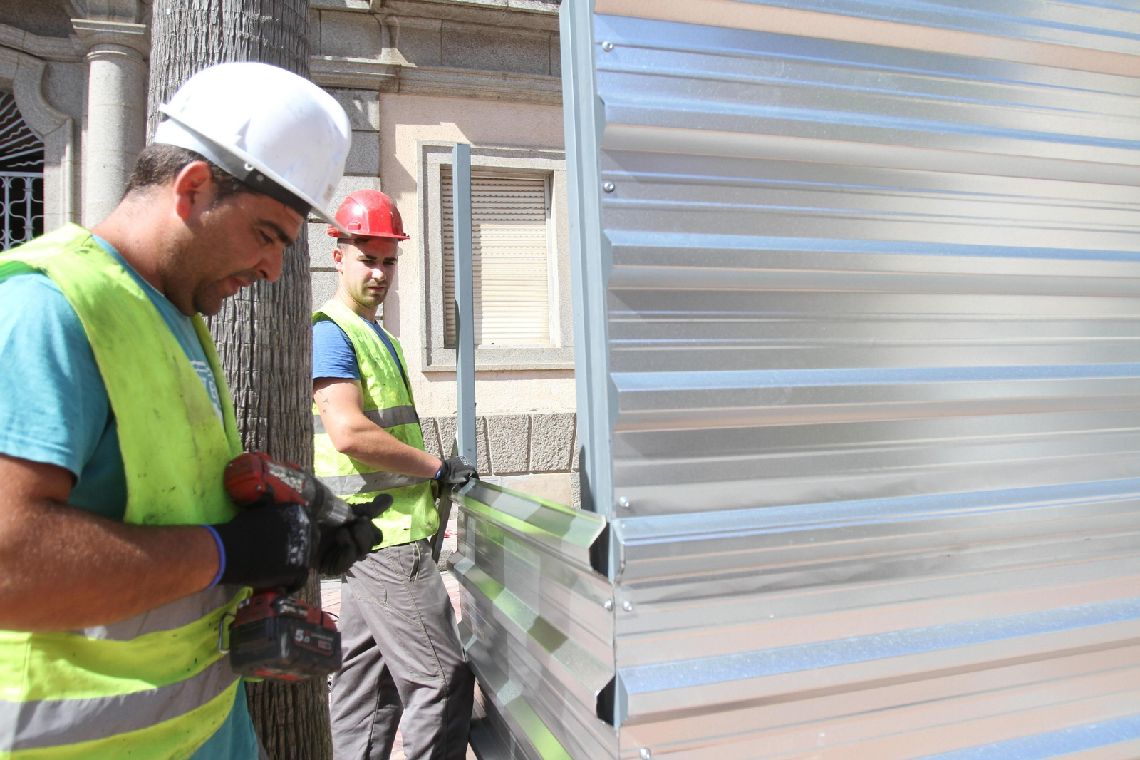 Dos operarios colocan el vallado exterior.