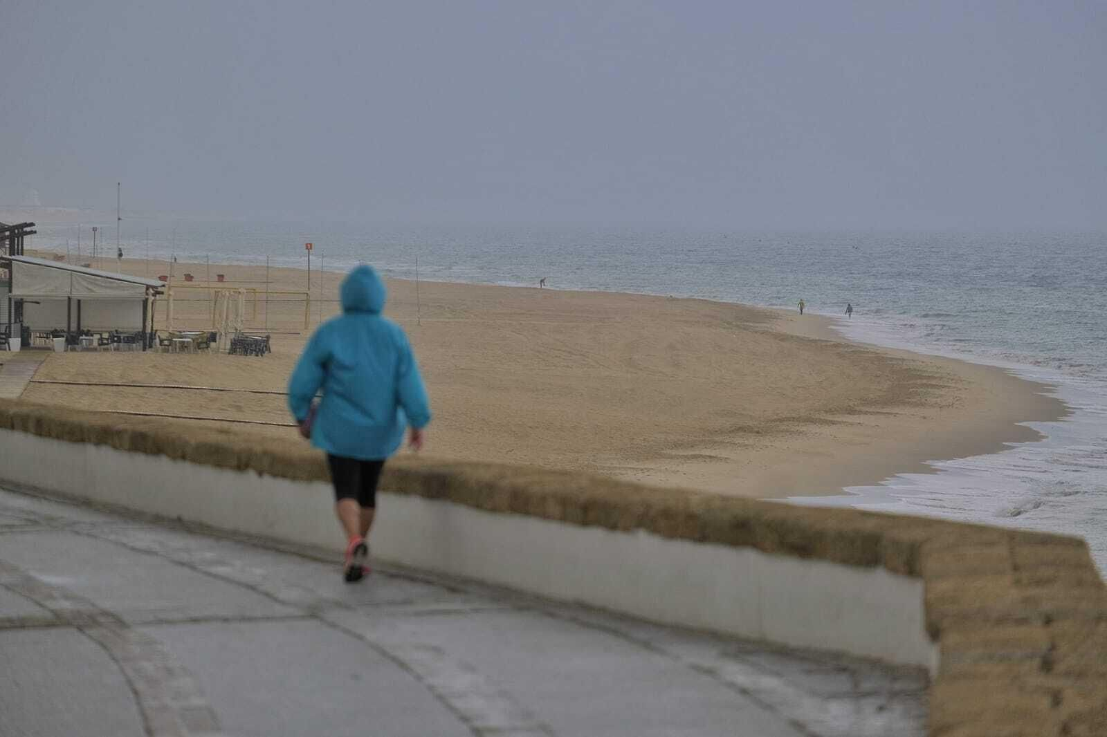 Sólo algún que otro paseante aprovechó el día para pasear con la playa de Cádiz, al fondo, totalmente vacía de bañistas