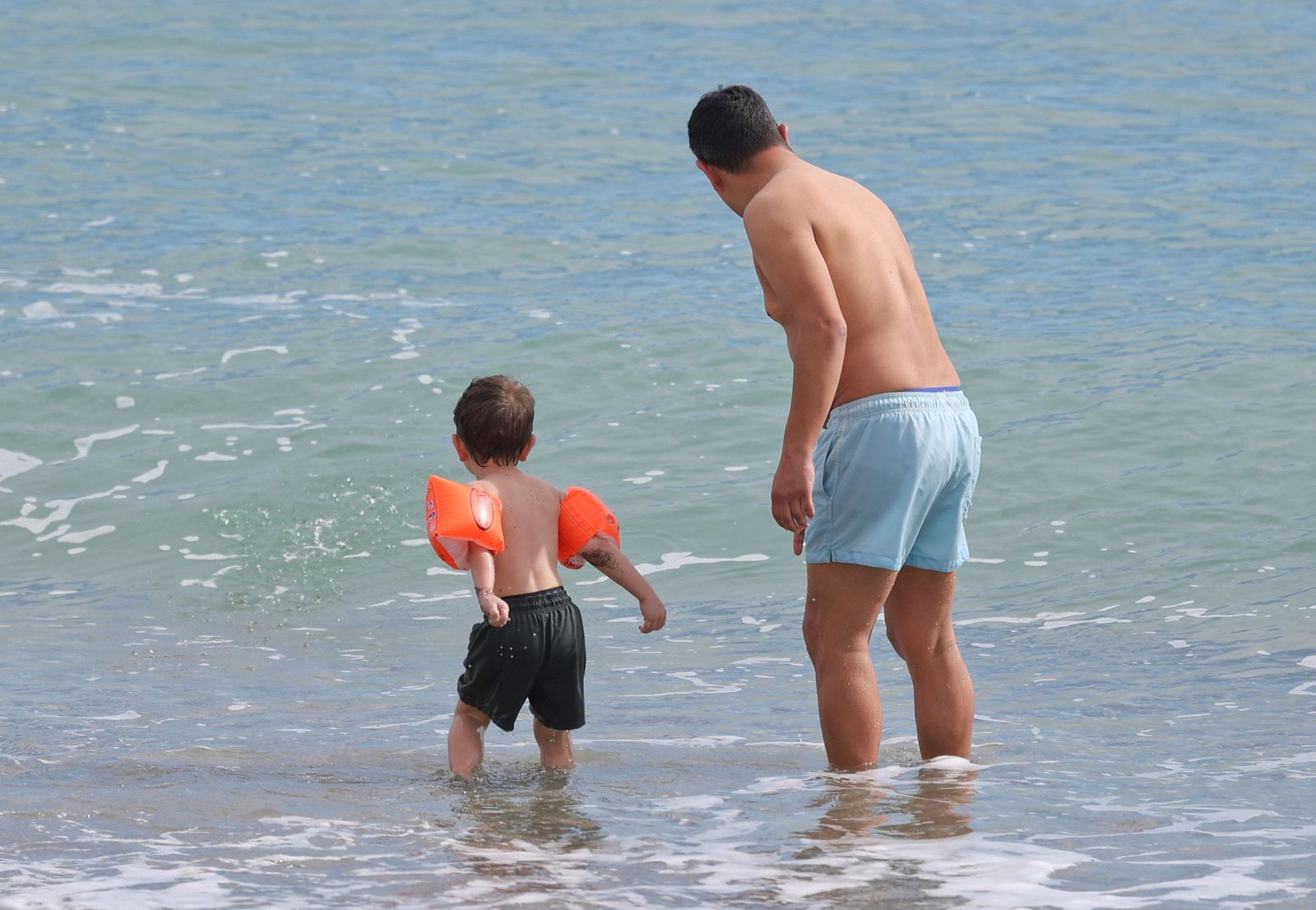 Un niño, junto a su padre, este miércoles en la playa en Málaga.