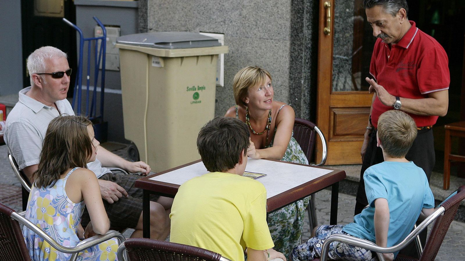 Contenedores  de recogida de basura  junto a las mesas de una terraza de un bar .