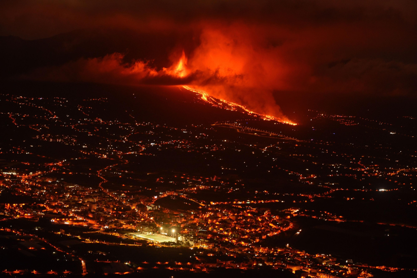 Imagen de la zona de El Paso iluminada durante la noche, con el volcán en erupción al fondo