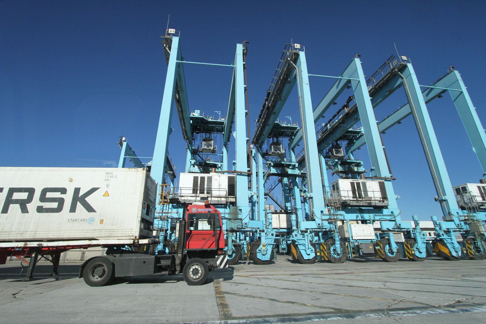 Un camión circula junto a varias grúas de patio en APM Terminals Algeciras.