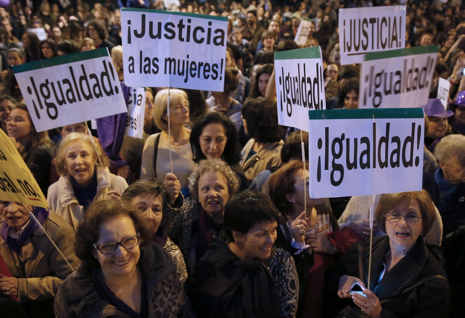 Un grupo de mujeres portan pancartas por la "igualdad" y la "justicia".