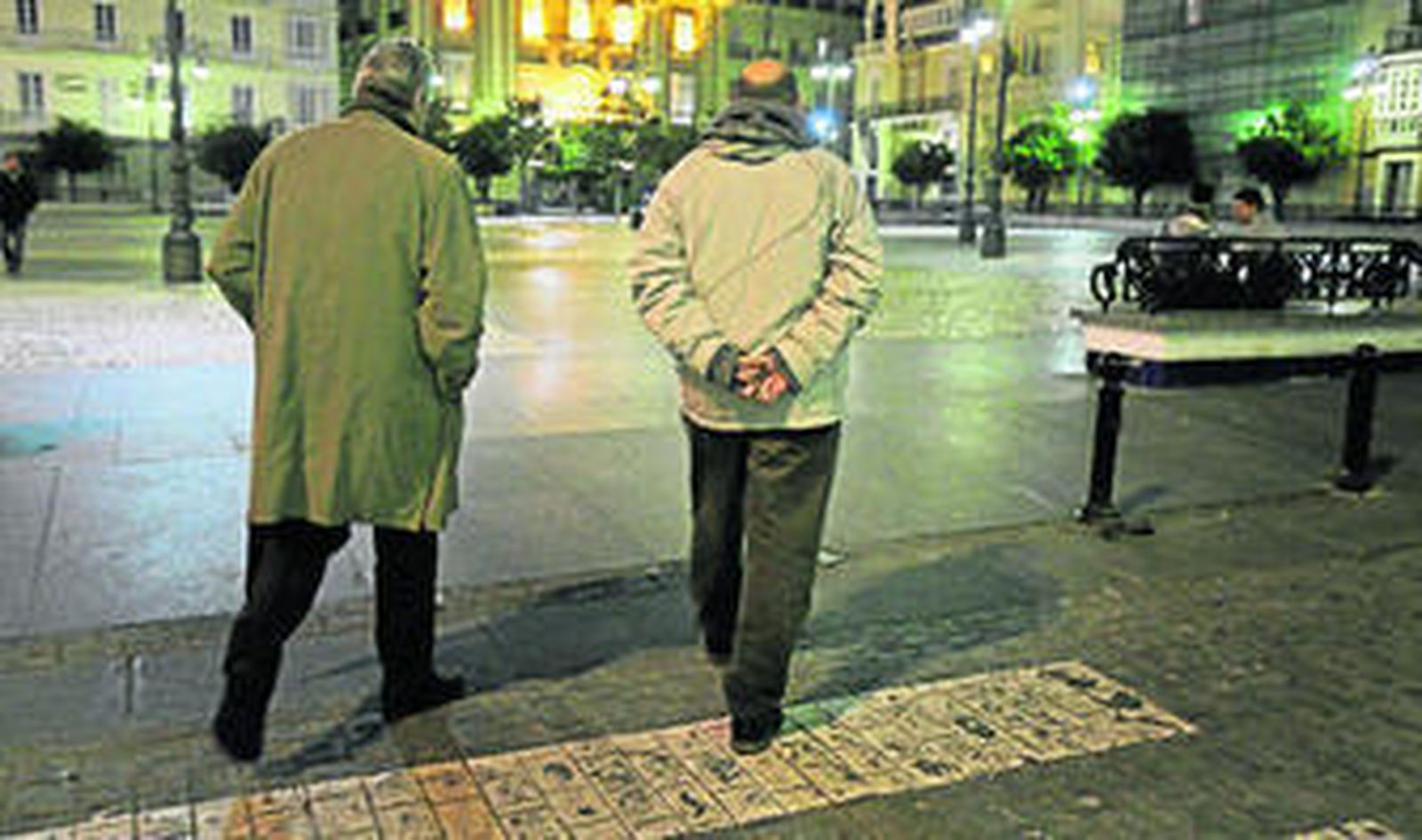 Ignacio García, de IU, (a la derecha) cruza cabizbajo la plaza de San Antonio de Cádiz la noche del domingo.