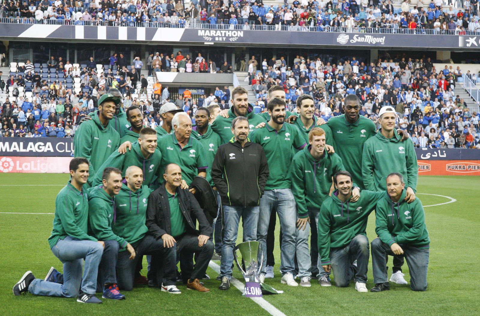 La plantilla del Unicaja posa con la Eurocup en el césped de La Rosaleda.