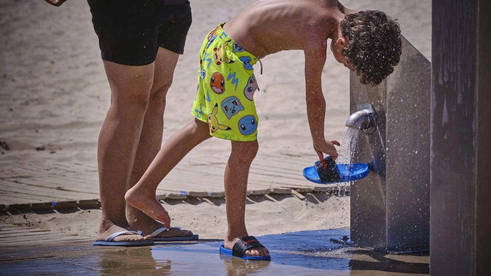 Un niño utiliza un lavapiés en una playa. Un niño utiliza un lavapiés en una playa.