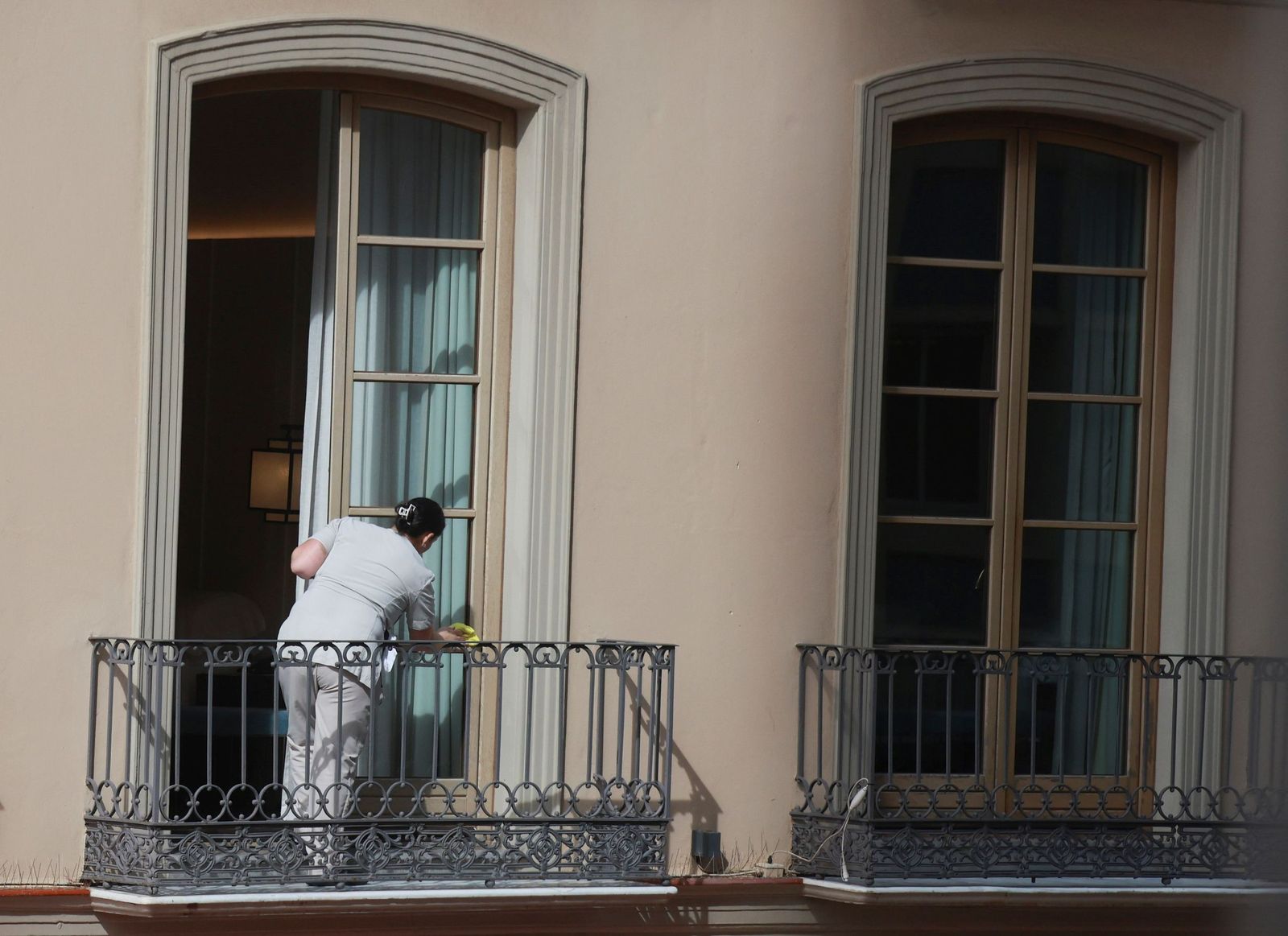 Una camarera de pisos para hoteles limpia una ventana | Imagen de archivo