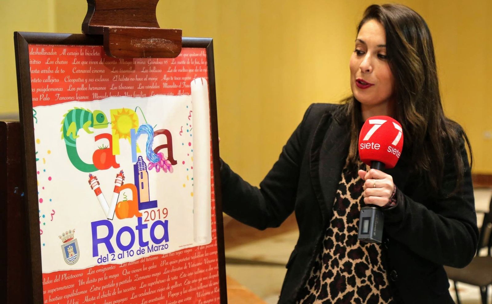 La autora del cartel explicando su diseño, que contiene los nombres de agrupaciones antiguas y recientes.