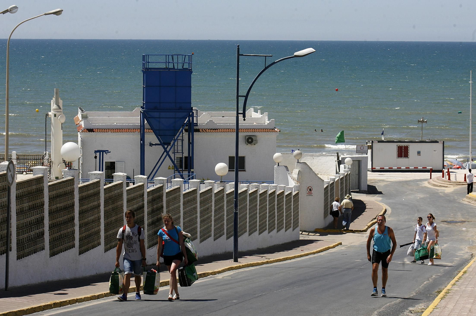 Varias personas atraviesan junto a la depuradora de Matalascañas (Huelva), objeto de una multa millonaria.