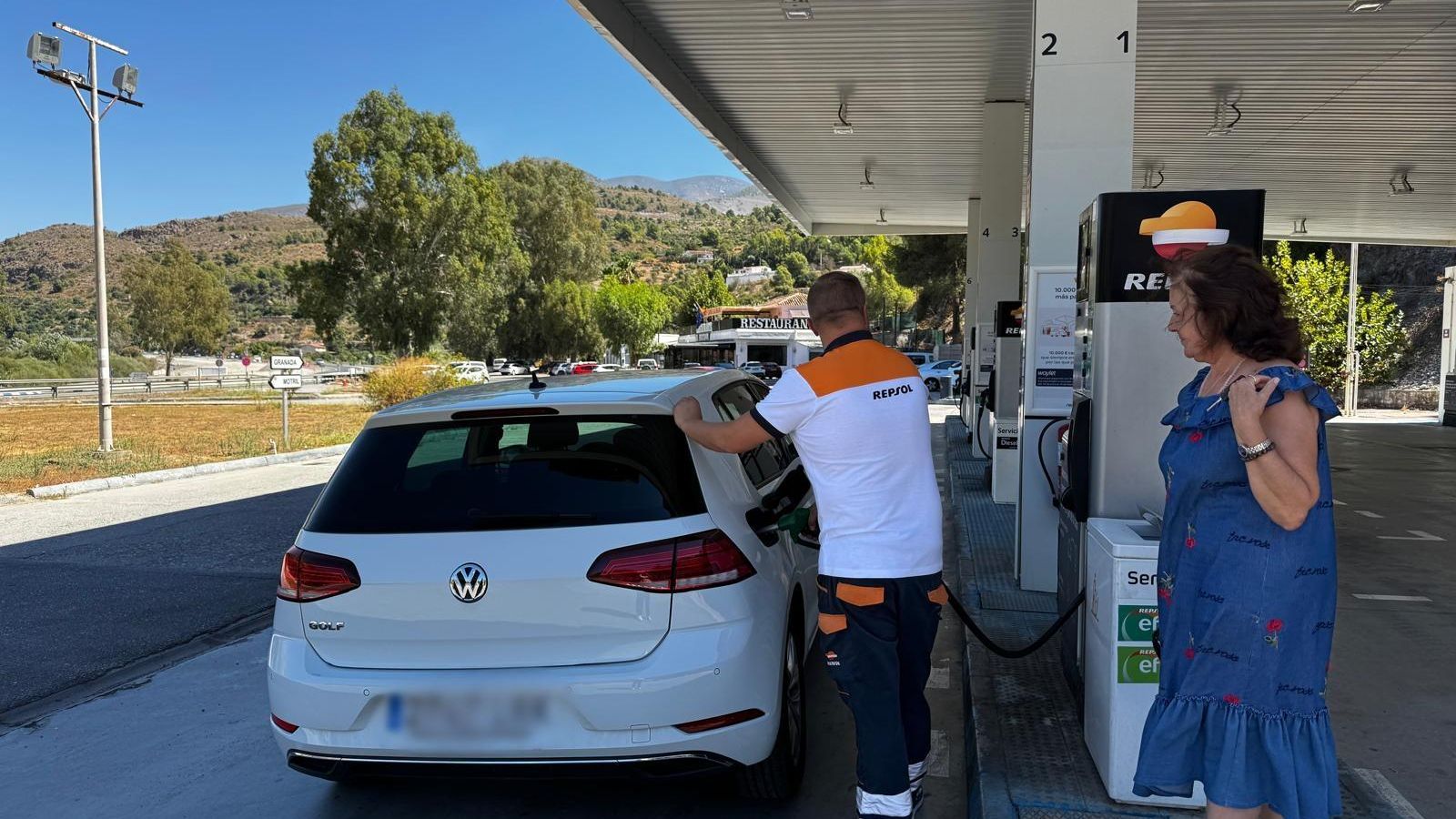 El encargado de la gasolinera repostando en el coche de una clienta