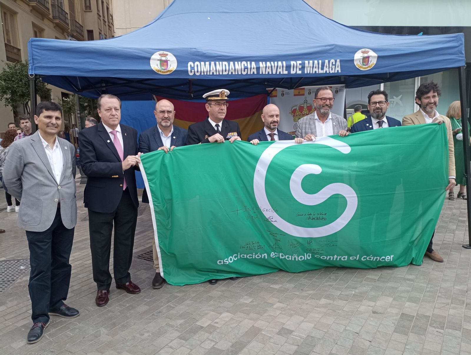 Autoridades sostienen la bandera de la AECC firmada, entre otros, por Antonio Banderas.