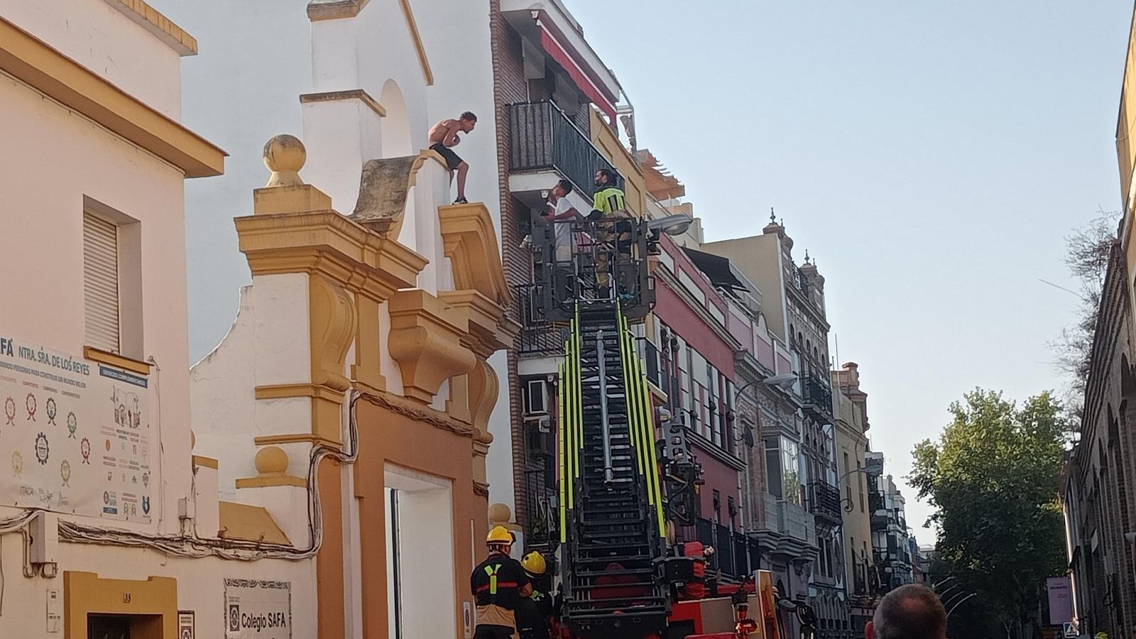 Un hombre subido en la fachada del colegio de la calle Calatrava en Sevilla