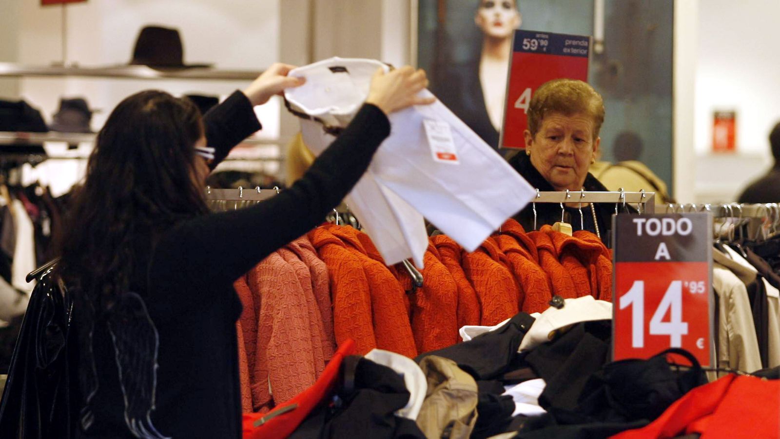 Varias personas miran prendas en una tienda de ropa mientras el precio del vestido registra fuertes subidas en varias provincias andaluzas.
