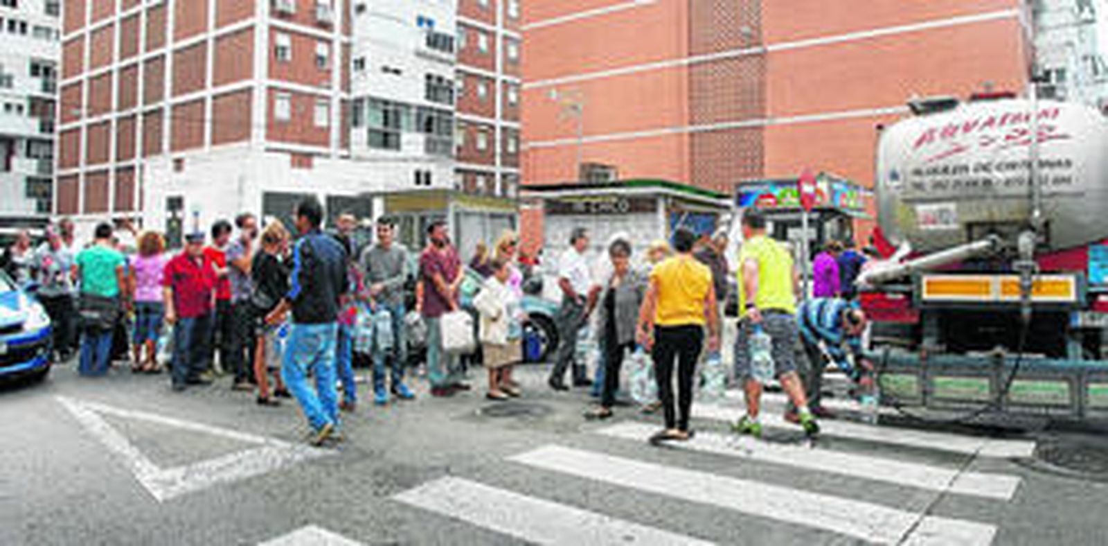 Los vecinos hacen cola, ayer, para recoger agua de un camión cisterna.