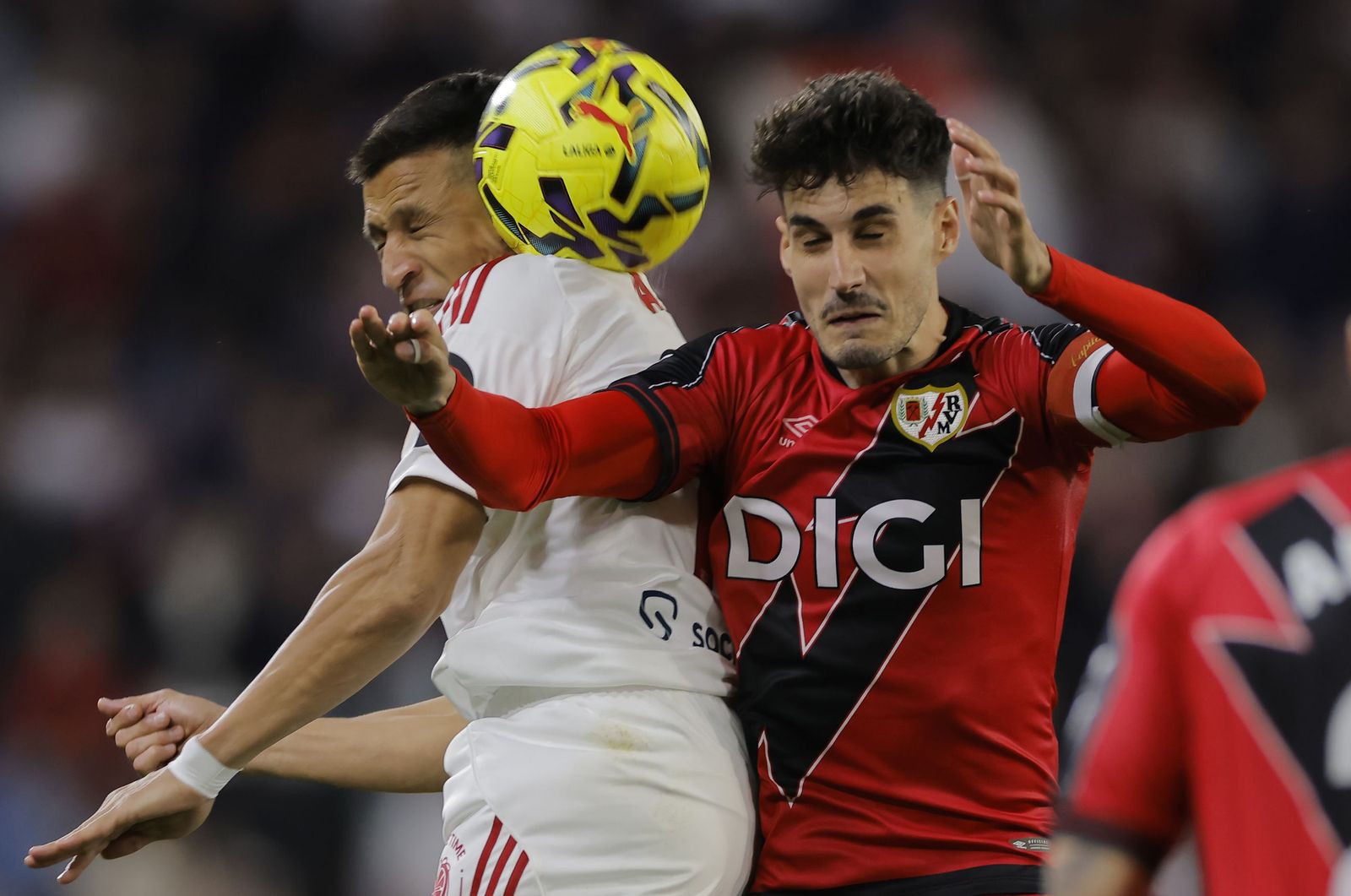 Alexis Sánchez, con los ojos cerrados, pelea un balón con Óscar Valentín, que también los tiene igual.