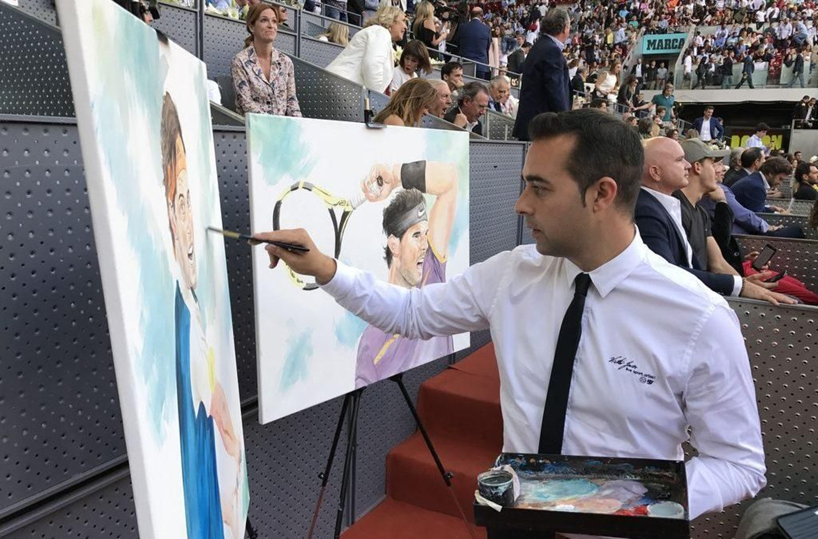 Víctor Jerez, junto a los cuadros de Rafa Nadal que realizó en directo en 2017.