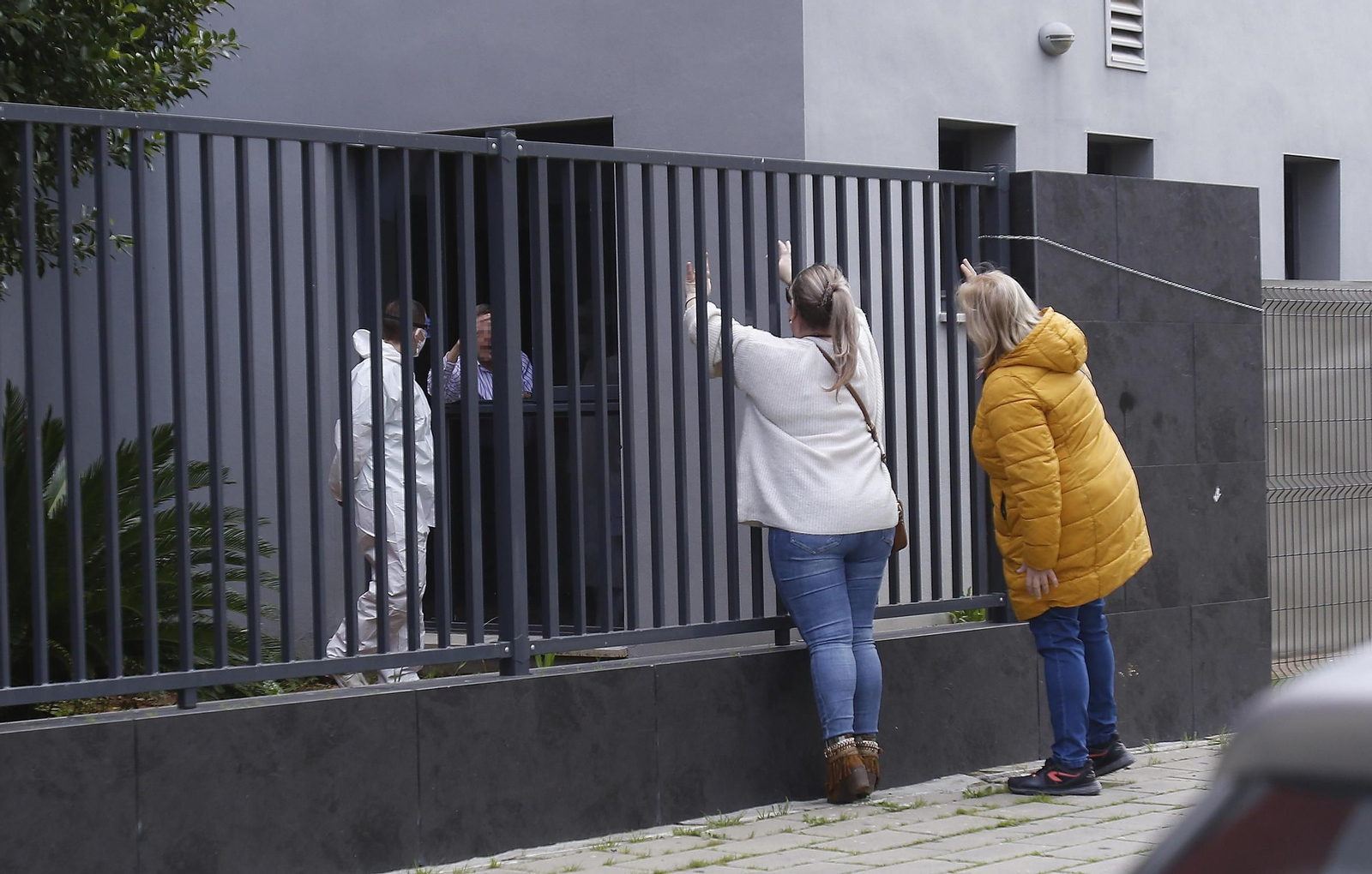 Dos familiares de usuarios tratan de hablar con los mayores por las ventanas.