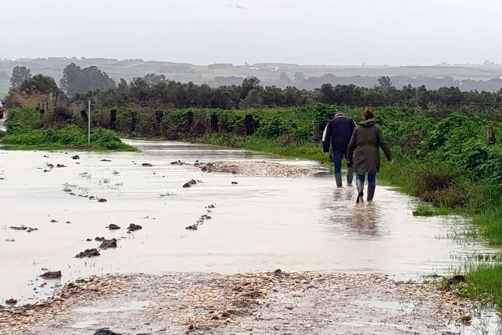 Dos personas cruzan una zona anegada de San Juan del Puerto.