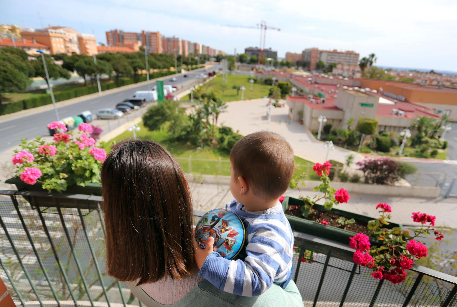 Un niño junto a su madre mira la calle desde la ventana de su vivienda. Un niño junto a su madre mira la calle desde la ventana de su vivienda.