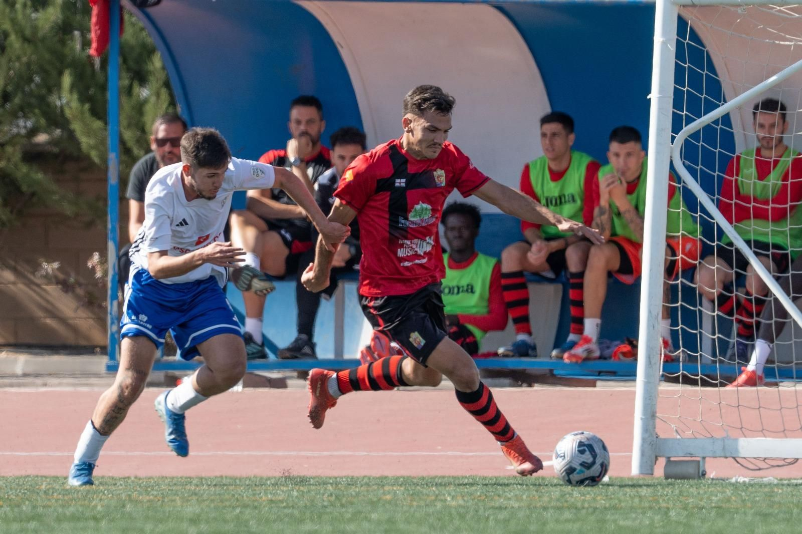 Un futbolista de cada equipo peleando por el balón.
