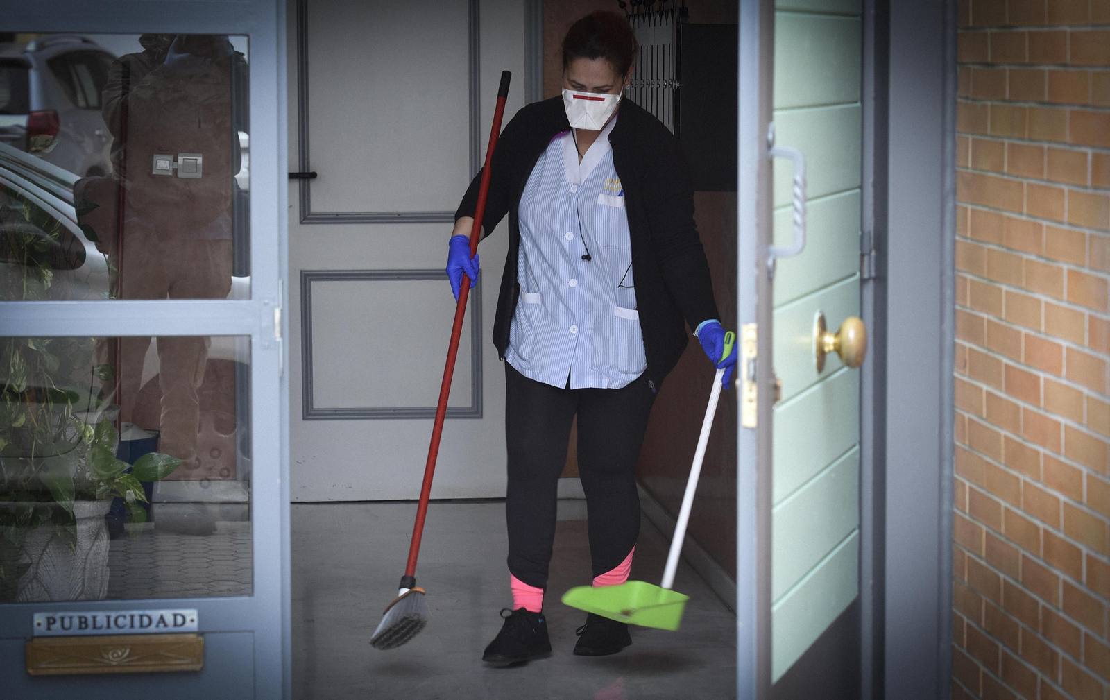 Una mujer limpia la puerta de una vivienda.