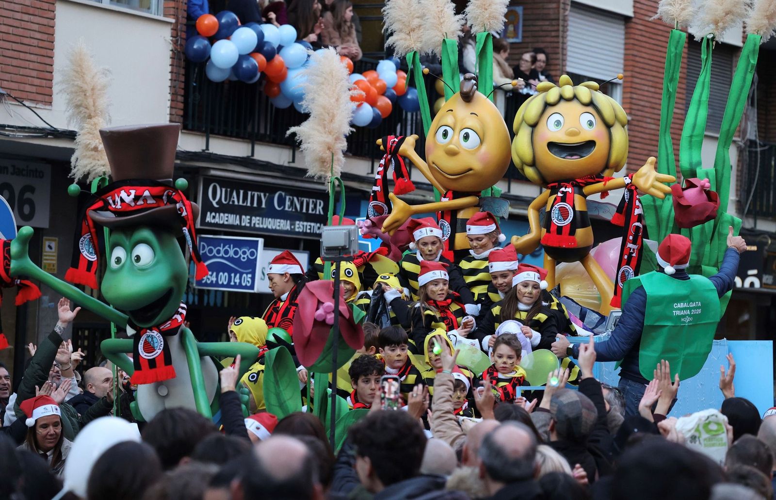 Varios niños sobre la carroza dedicada a la Abeja Maya tiran los últimos caramelos del 6 de enero.