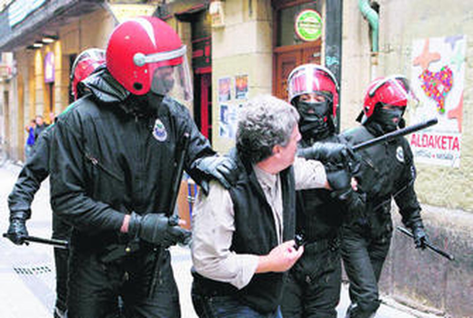 Varios ertzainas se llevan detenido a uno de los participantes en la manifestación ilegal.